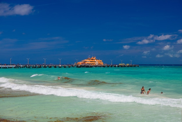 Oranje veerboot in azuurblauwe oceaan met zwemmende mensen in playa del carmen yukatan mexico