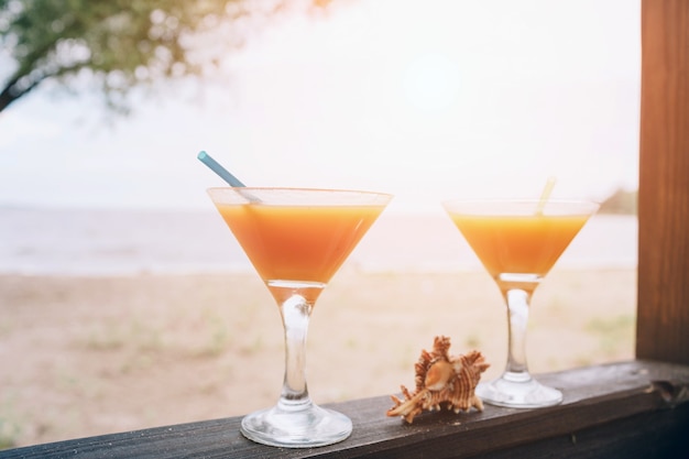 Oranje verse exotische cocktails op houten rand. Schelp die tussen glazen ligt. Leven op het eiland