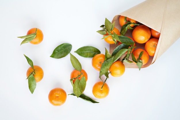 Oranje verse mandarijnen met groene bladeren in een papieren zak