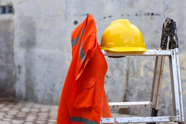 Oranje vest en gele veiligheidshelm voor bescherming van de werkveiligheid op de bouwplaats