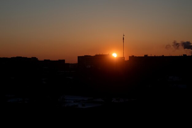 Oranje zonsondergang over daken van gebouwen met meerdere verdiepingen aan de horizon, stedelijke achtergrond