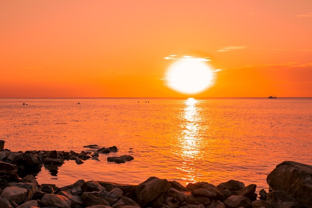 Oranje zonsondergang over de zee met een rotsachtige kust Zee zonsondergang landschap