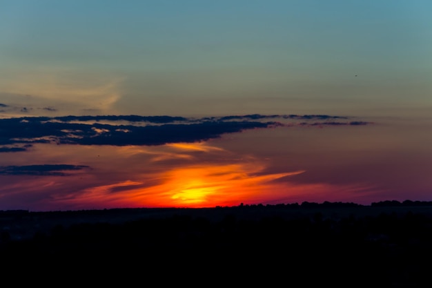 Oranje zonsondergang over silhouetten van dorp en bomen