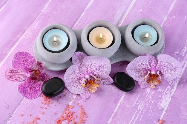 Orchid flowers spa stones and sea salt on color wooden background