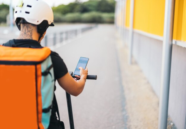 Order delivery person using smartphone on electric scooter