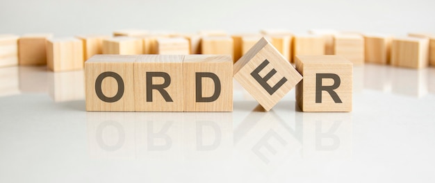 Order - word of wooden blocks with letters on a gray background. reflection of the caption on the mirrored surface of the table. selective focus.