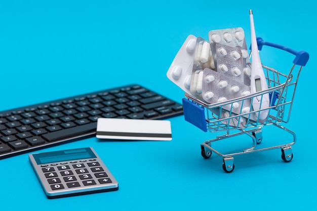 Foto ordinare medicinali pillole e capsule in un carrello su sfondo blu