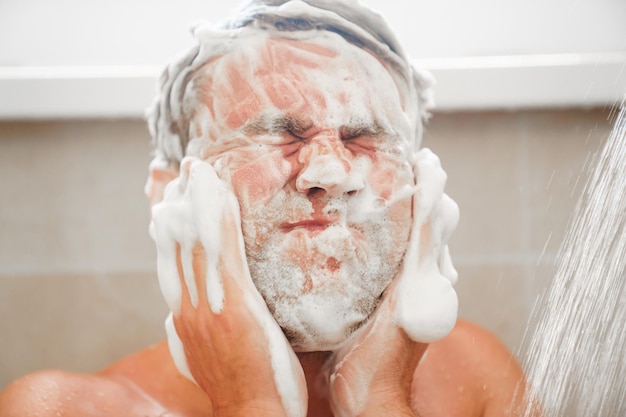 An ordinary man washes hair and face with soap or shampoo closeup