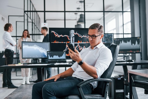 Ordinary office day Team of stockbrokers works in indoors with many display screens