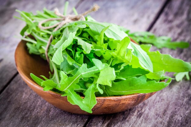 Organic arugula bundle in a wooden bowl on a rustic table