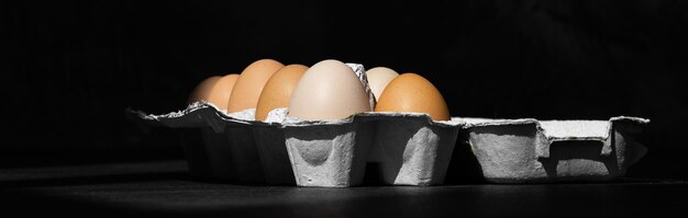 Organic chicken eggs on dark wooden background with copy space