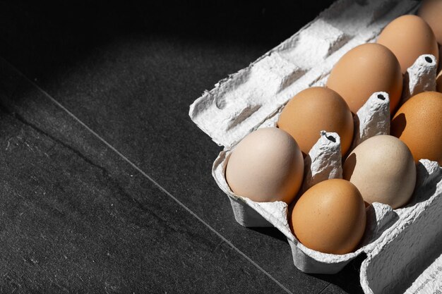 Organic chicken eggs on dark wooden background with copy space