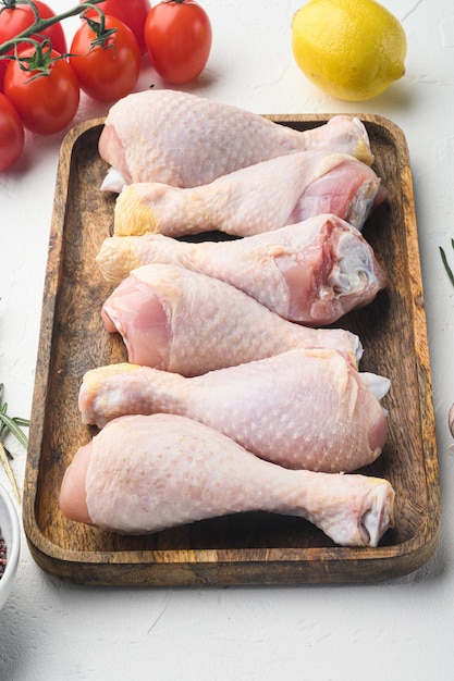 Organic chicken legs with spices and garlic set on white background