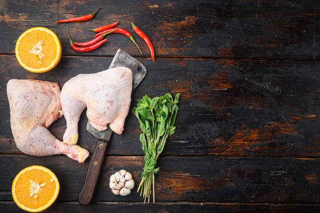 Organic chicken legs with spices and garlic set , with old butcher cleaver, on old dark wooden table, top view flat lay