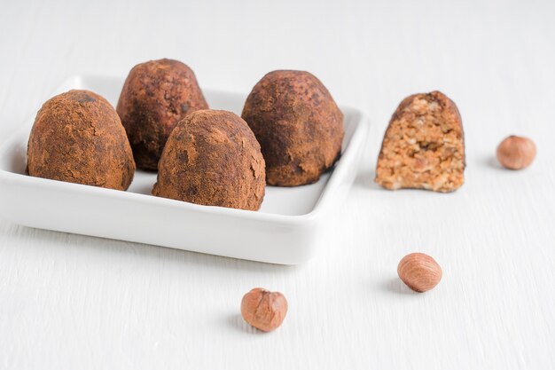 Organic chocolate vegetarian truffles made of hazelnuts with cocoa powder served on plate on a table