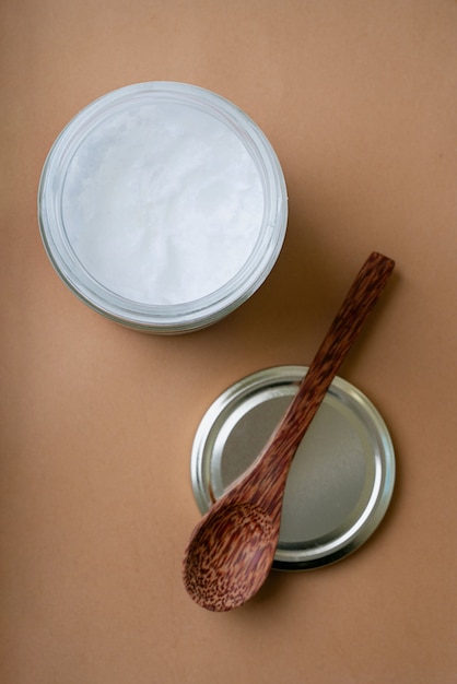Organic coconut oil in the glass jar  with coconut spoon. Sustainability concept. Top View. Flat Lay.