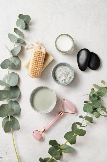 Organic cosmetic clay brush massage stone and eucalyptus branch on a white textured background The concept of spa and wellness Top view