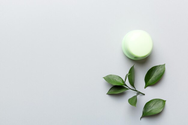 Органический косметический продукт с зелеными листьями на цветном фоне
