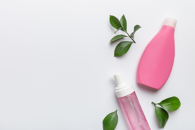 Organic cosmetic products with green leaves on white background. Copy space, flat lay.