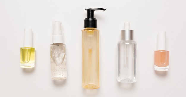 Дизайн упаковки органической косметики. Плоская планировка, прозрачная стеклянная бутылка с насосом, вид сверху, баночка для кисти, баночка для увлажняющей сыворотки на белом фоне. Натуральная косметика SPA