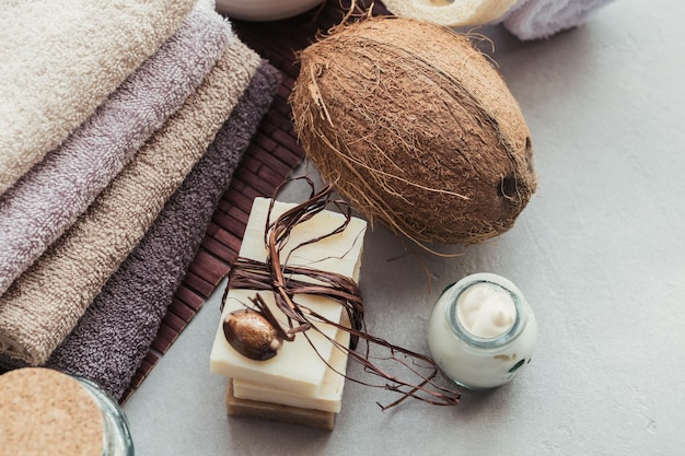 Organic cosmetics with coconut oil sea salt towels and handmade soap on grey background