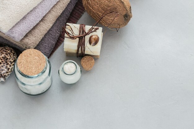 Organic cosmetics with coconut oil, sea salt, towels and handmade soap on grey surface. Natural ingredients for homemade facial and body mask or scrub. Healthy skin care. SPA concept.