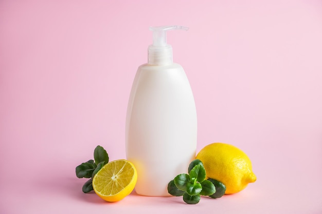 Organic cosmetics with lemon oil Bottle of moisturizer with citrus on a pink background