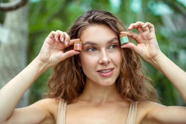 Organic cosmetics. Young woman holding jars with eyeshadows in her hands