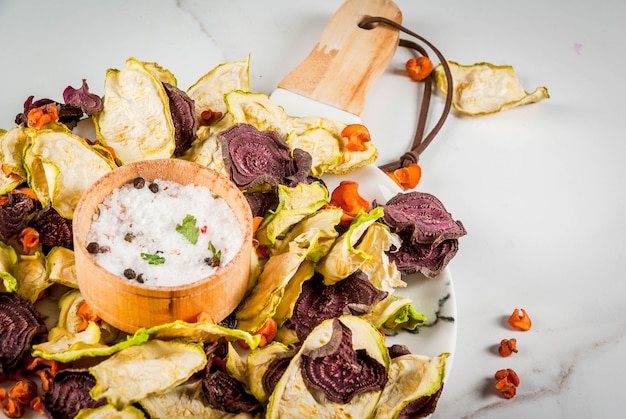 Foto alimenti dietetici biologici la dieta vegana verdure secche patatine fritte di barbabietole, carote e zucchine. su un tavolo di marmo bianco, con verdure fresche. copyspace