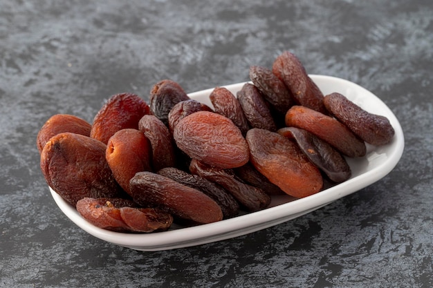 Organic dried apricots on plate on dark background