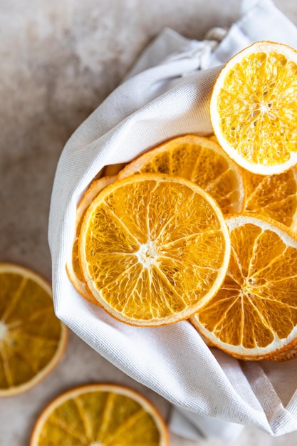 Organic dried orange chips in eco canvas bag on light concrete background