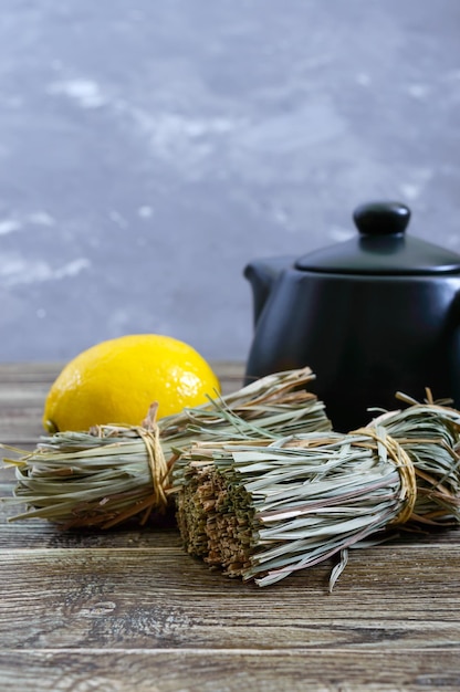 Organic dry lemongrass (Cymbopogon flexuosus) in bunches and lemon fruit on a wooden table. Herbs for tea.