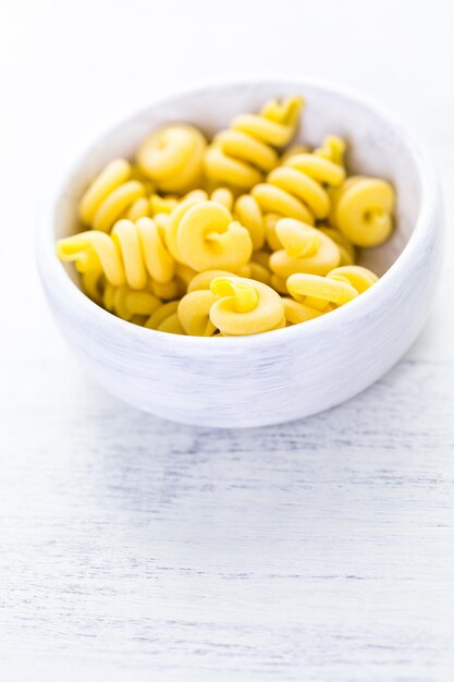 Organic dry pasta in small round bowl.