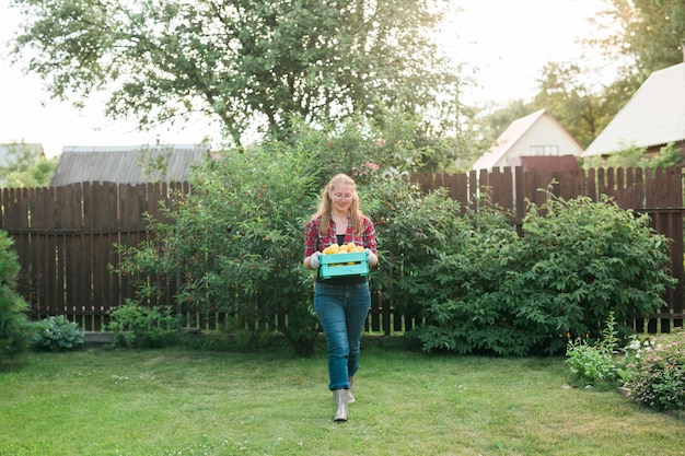 Фото Органическая женщина-фермер держит коробку со свежими продуктами на своей ферме, копирует пространство и место для текста ха