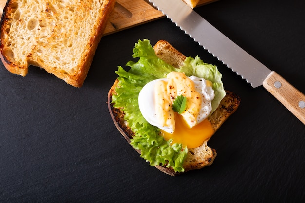 Photo organic food breakfast concept homemade poached egg or eggs benedict on sourdough bread toasted on black slate board