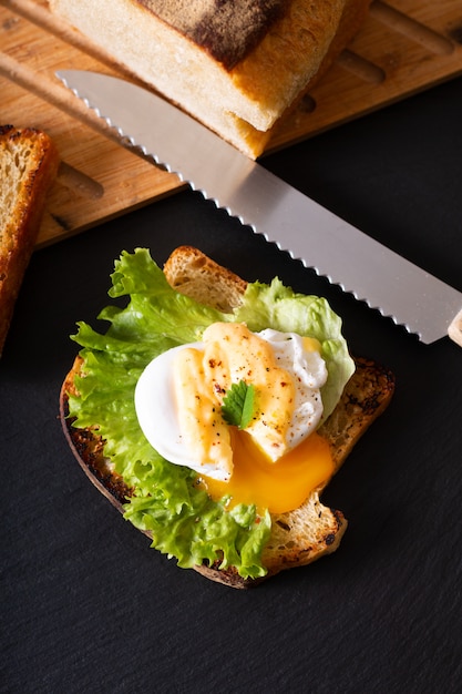 유기농 식품 아침 식사 개념 블랙 슬레이트 보드에 구운 효 모 빵에 만든 데친 된 달걀 또는 계란 베네딕트