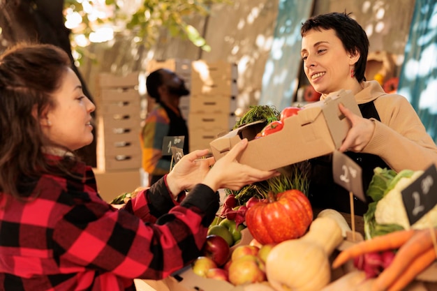 Органические продукты с местного сельскохозяйственного рынка, клиент покупает свежие травы и покупает свежие продукты на фермерском рынке. Владелец малого бизнеса, обслуживающий женщину, продающий домашние фрукты и овощи.