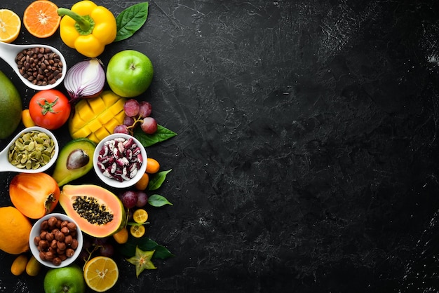 Organic food Fruits vegetables beans and nuts on a black stone background Top view Free space for your text