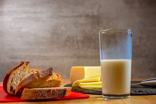 유기농 식품. 나무 테이블에 신선한 치즈와 빵 조각. 우유 한 잔