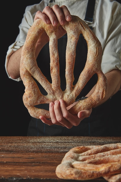 Organic fresh fougas bread in the hands man on a black background