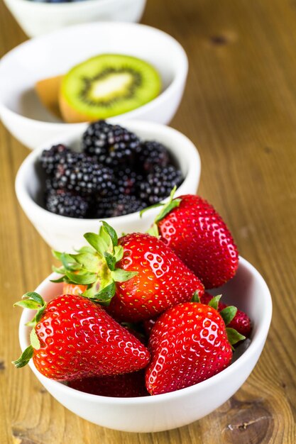 Organic fresh fruit in round bowls on wood table.