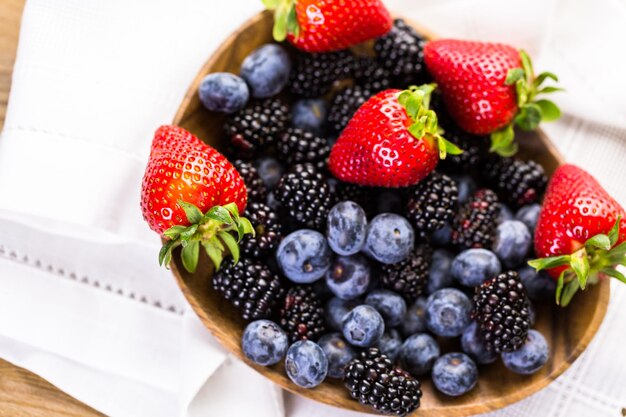 Organic fresh mixed fruit in wood bowl on the table.