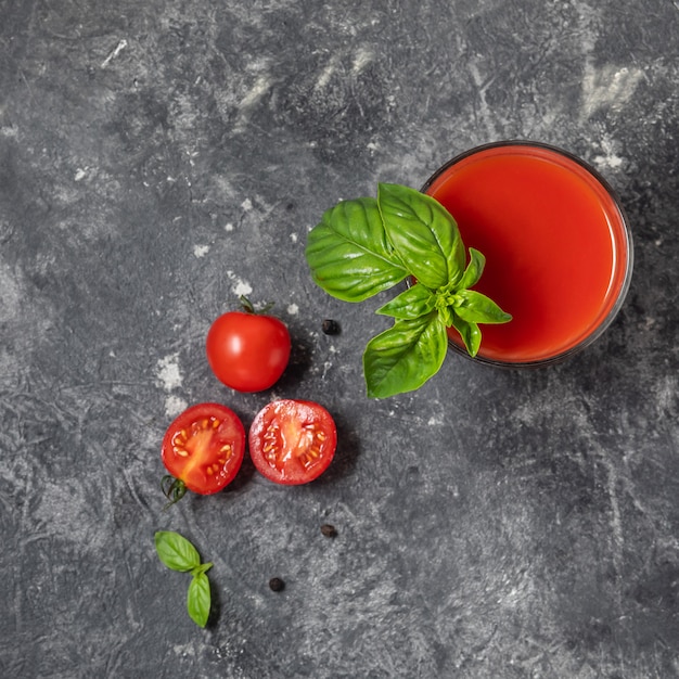 Foto succo di pomodoro fresco organico in un bicchiere su uno sfondo scuro.