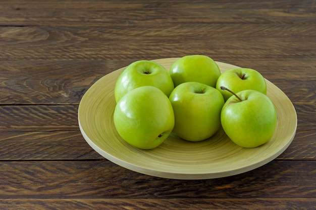 Organic Granny Smith apples on a plate on wooden table.