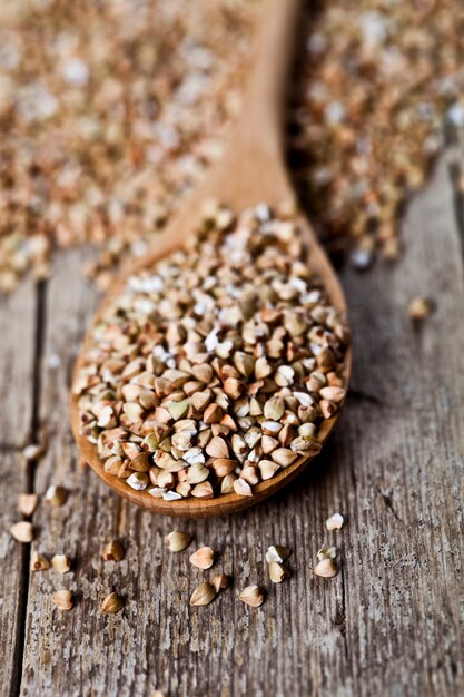 Organic green dry buckwheat seads in wooden spoon