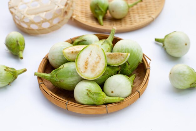 Organic green eggplant in bamboo basket on white background.