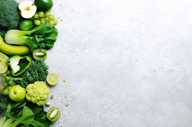 Photo organic green vegetables and fruits on grey. copy space, flat lay, top view. green apple, lettuce, zucchini, cucumber, avocado, kale, lime, kiwi, grapes, banana, broccoli