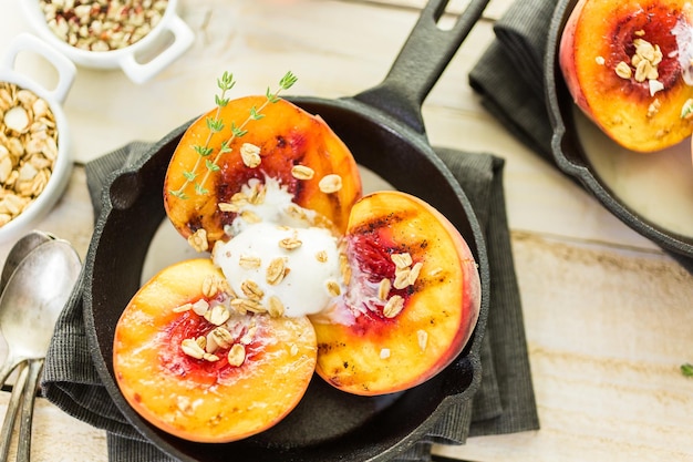 Organic grilled peaches with scoop of vanilla ice cream on a cast iron frying pan.