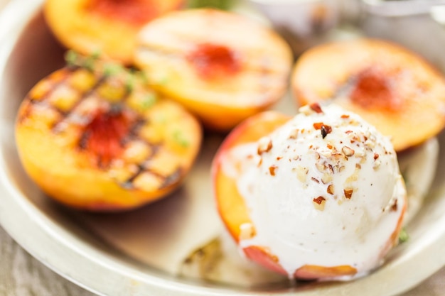 Photo organic grilled peaches with vanilla ice cream, honey, and pecans.