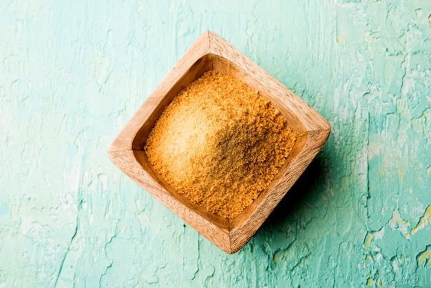 Organic Gur or Jaggery Powder is unrefined sugar obtained from concentrated sugarcane juice. served in a bowl. selective focus